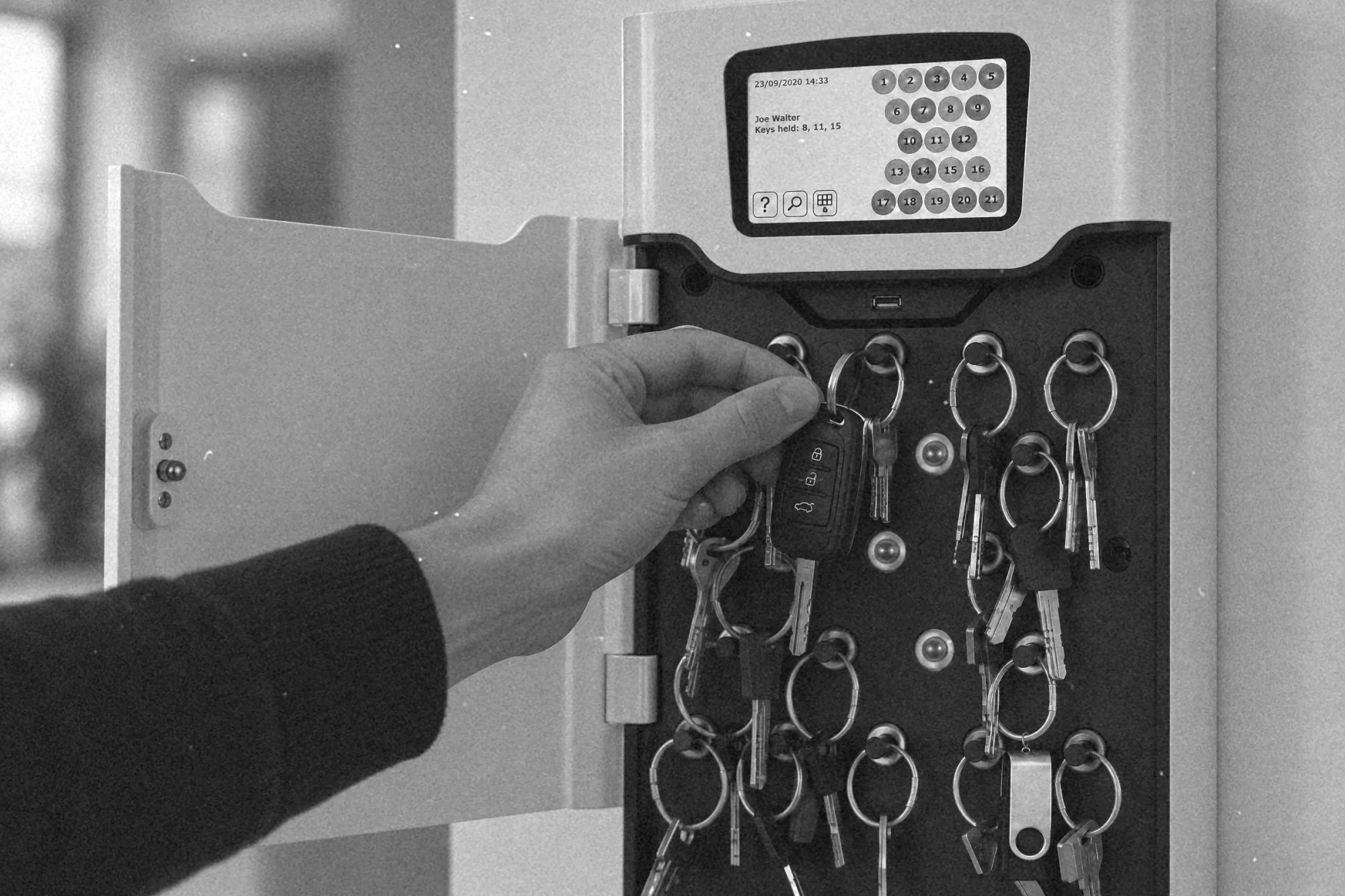 Dłoń zdejmująca kluczyk samochodowy z gniazda depozytora kluczy