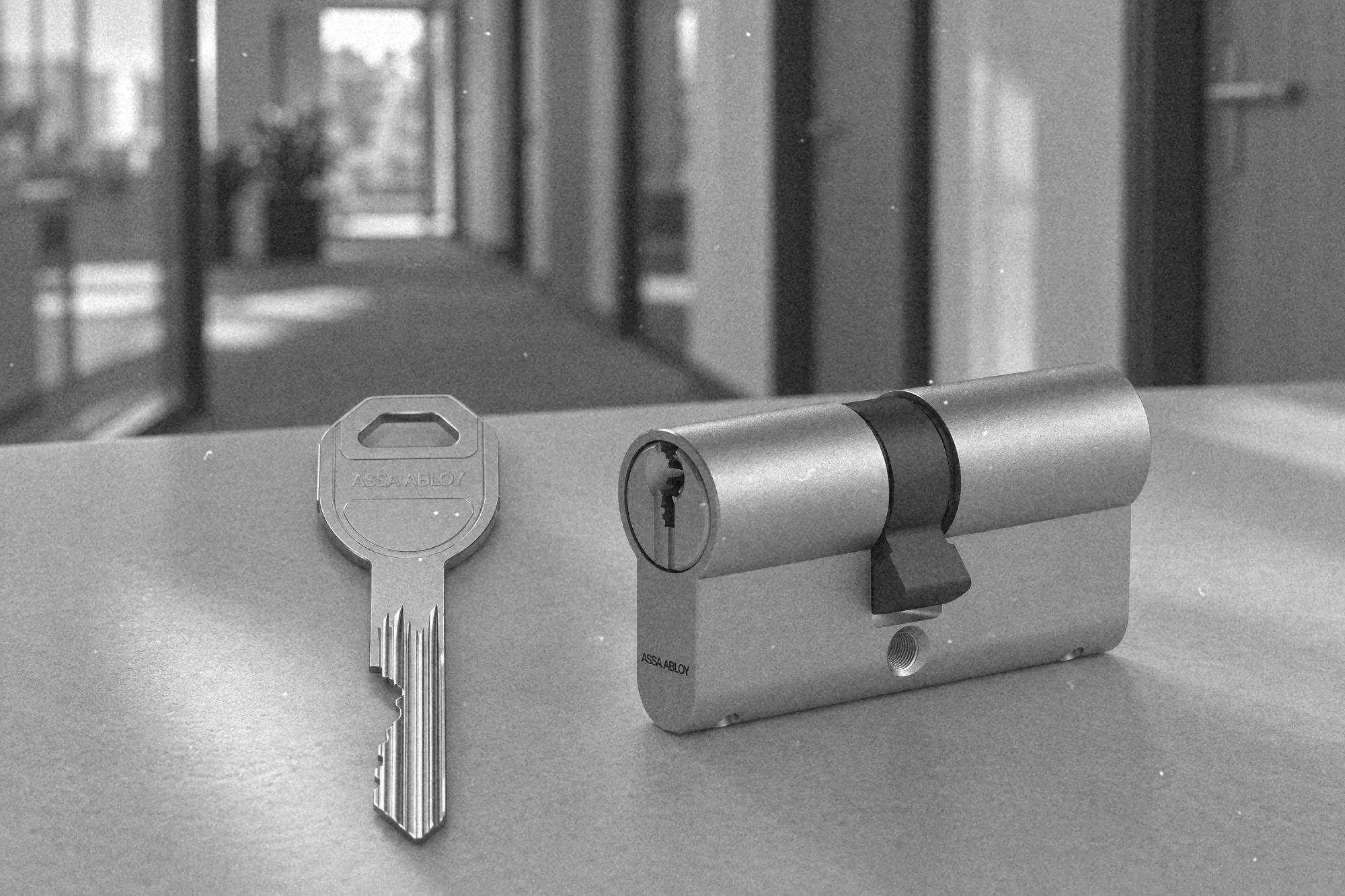 Klucz generalny systemu Master Key obok wkładki bębenkowej na tle korytarza z drzwiami