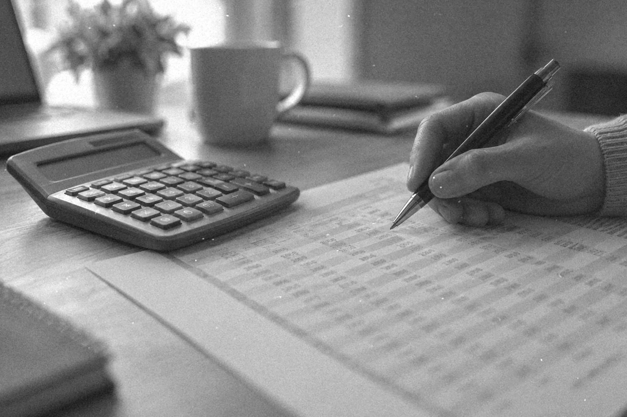 Wydrukowana wycena zestawu i kalkulator na biurku, dłoń z długopisem