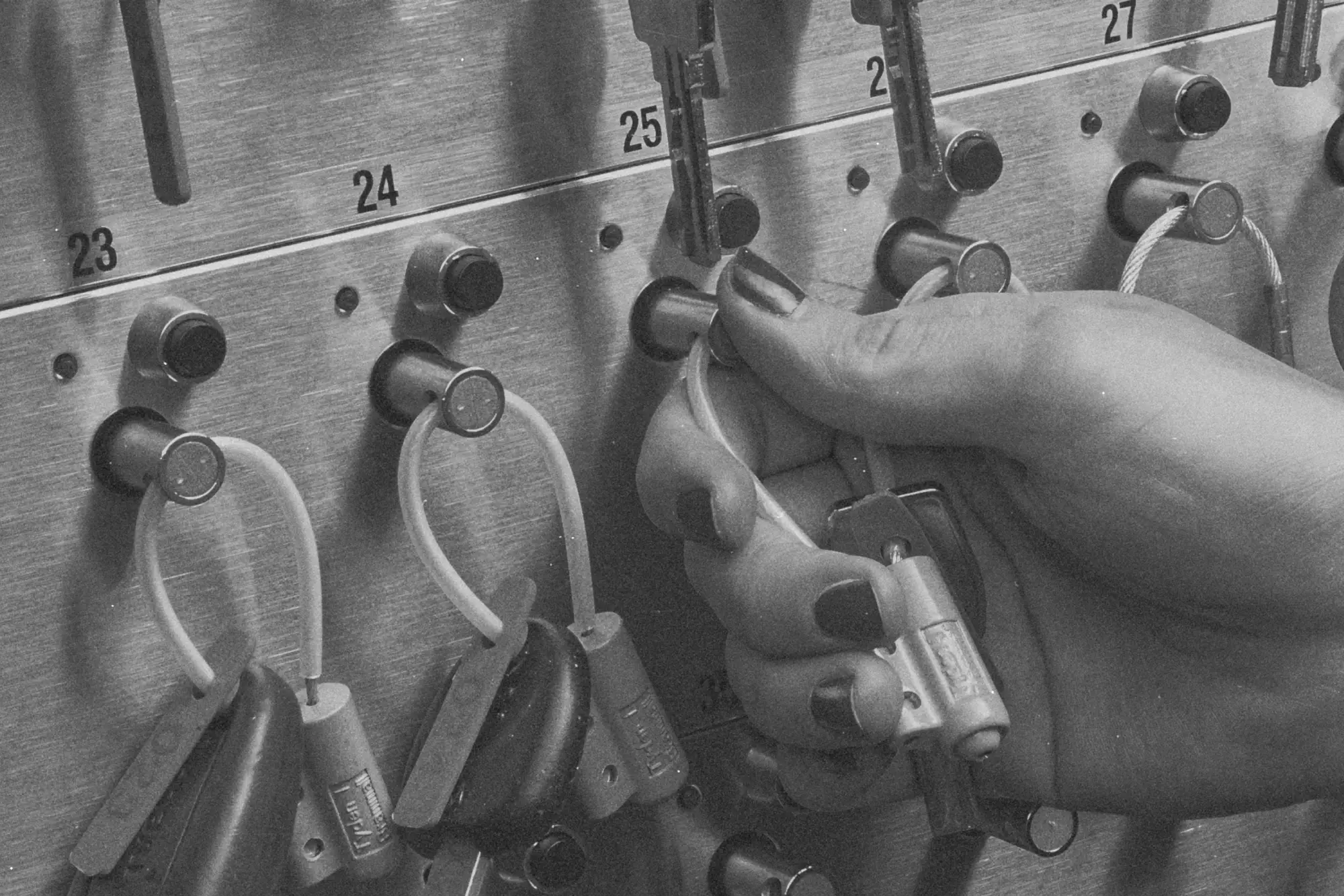 Dłoń wyjmuje brelok z kluczami z numerowanego gniazda depozytora kluczy