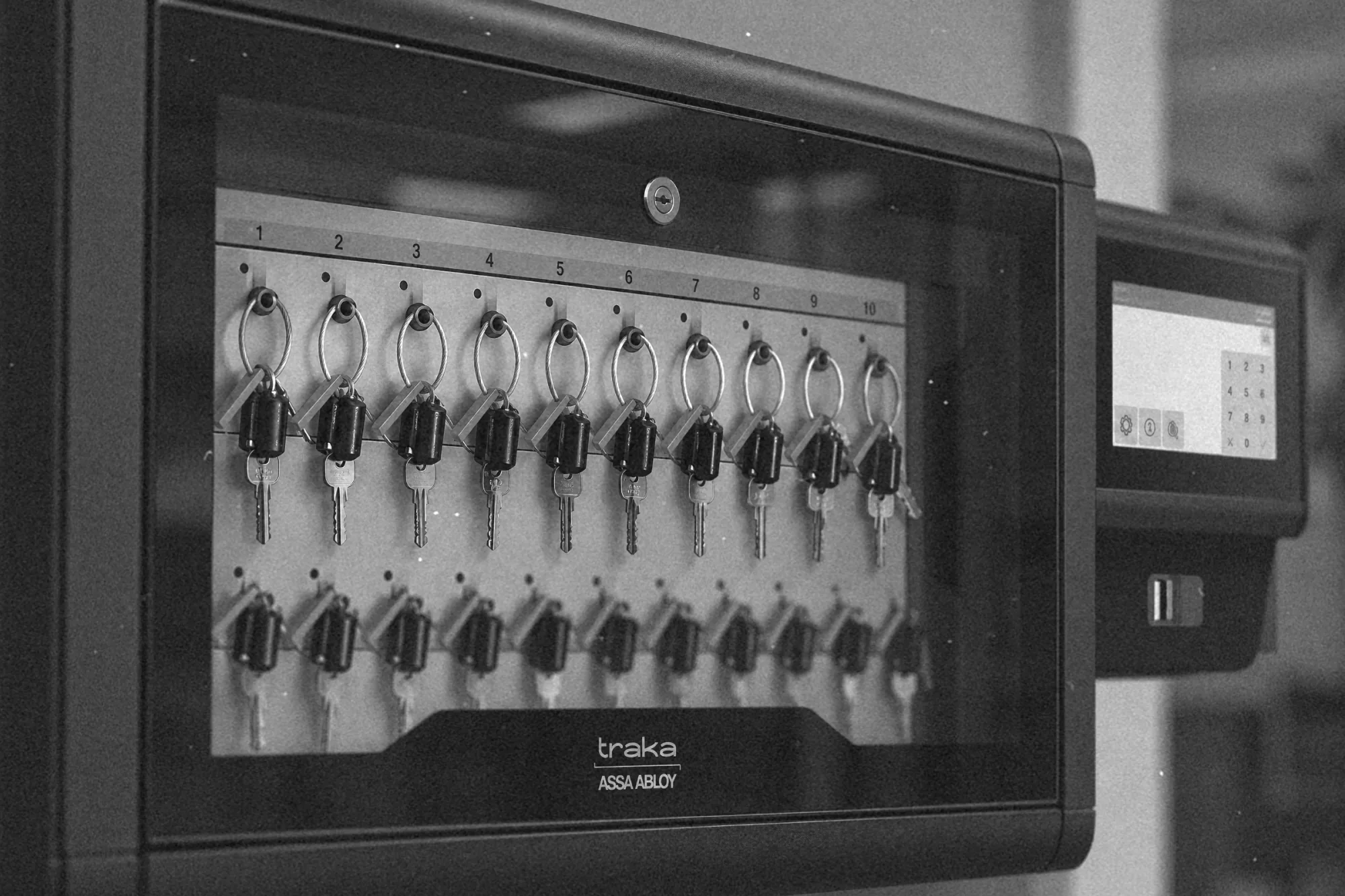 Szereg numerowanych gniazd depozytora kluczy z breloczkami RFID, widok z bliska