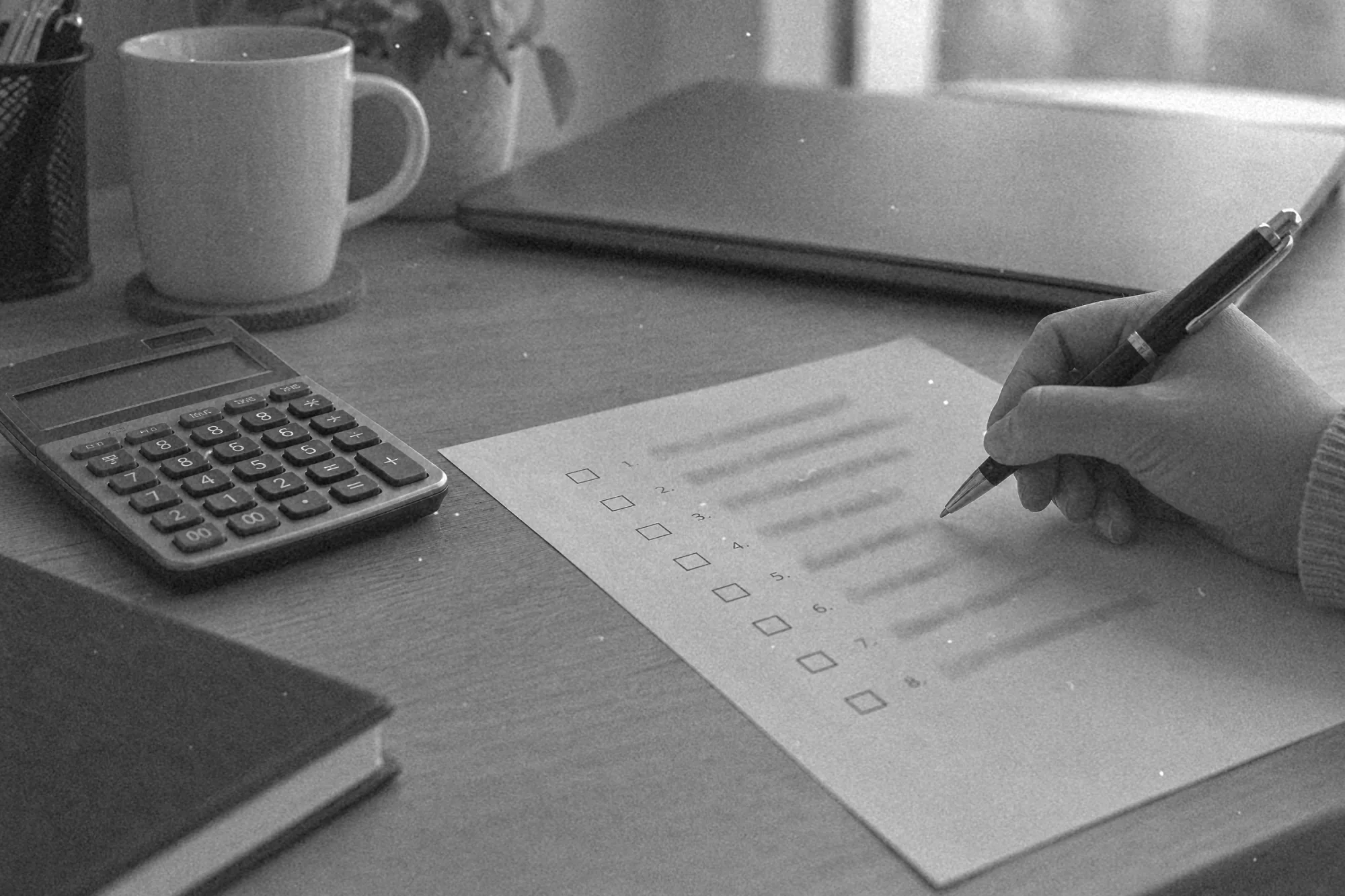 Kartka z listą pytań do sprzedawcy i kalkulator obok laptopa